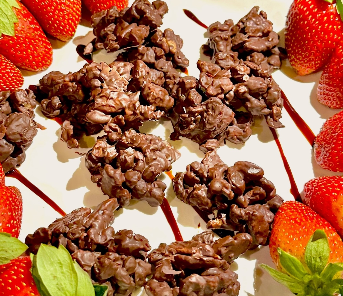 Vegan chocolate candies fruit and nut clusters pictured with date glaze and strawberries.