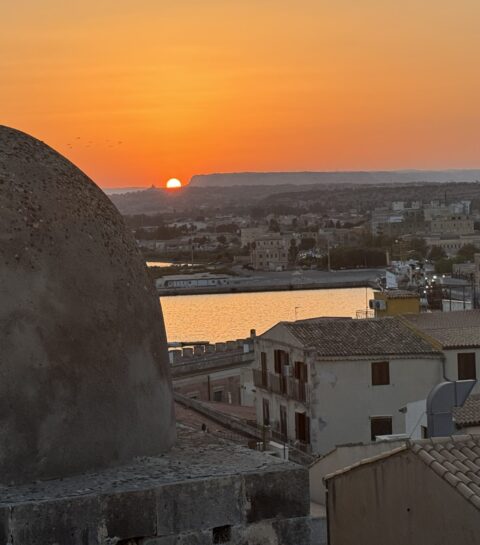 A photo from the Isola di Ortigia, an island that is the historic center of Siracusa, Sicily. The view of Siracusa with Mt. Etna in the background.